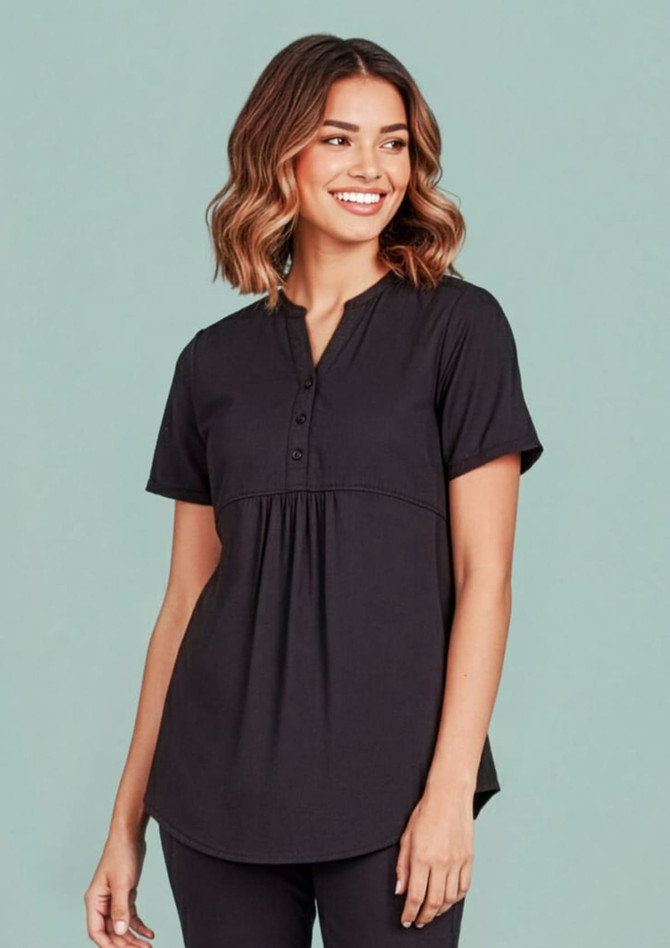 A women's black tunic scrub top featuring a buttoned neckline and a relaxed fit. The top has a logo on it.