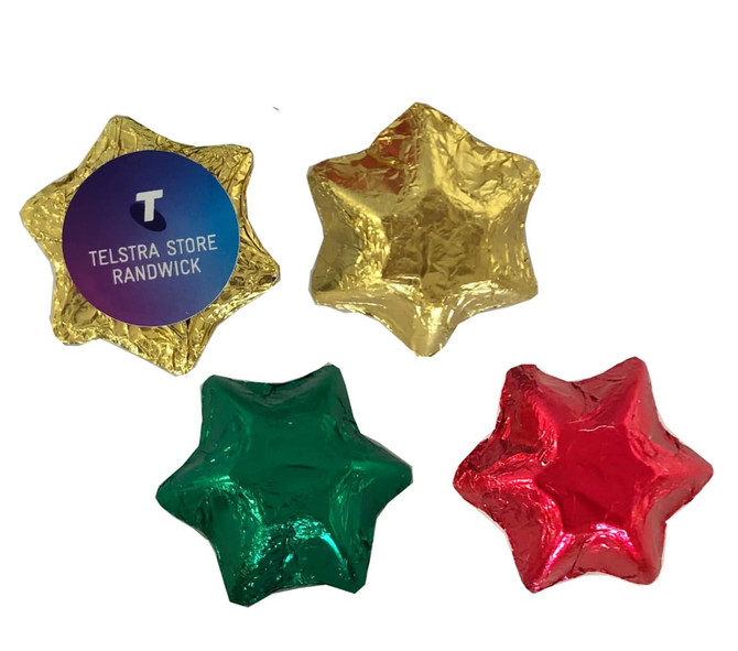 Four star-shaped chocolates wrapped in gold, green, and red foil, with a branding logo on one.