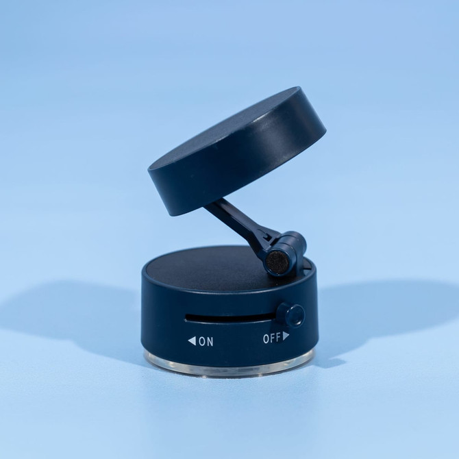 A black and silver vacuum suction phone stand with a rotating top and an on/off switch. It features a logo.