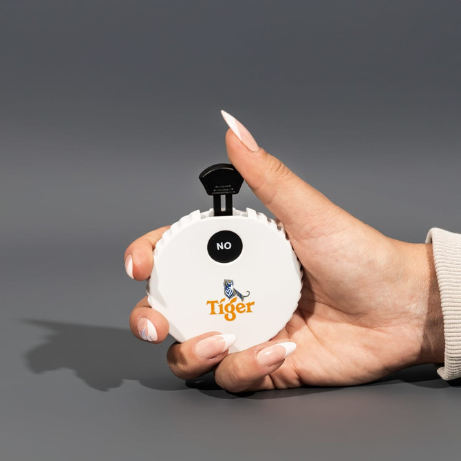 A white, circular spinner with a black lever, held in a hand, featuring a logo on the front.