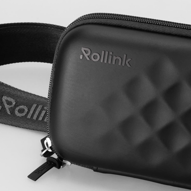 A black mini bag with a textured surface and a strap, featuring a logo on the front and a zip closure.