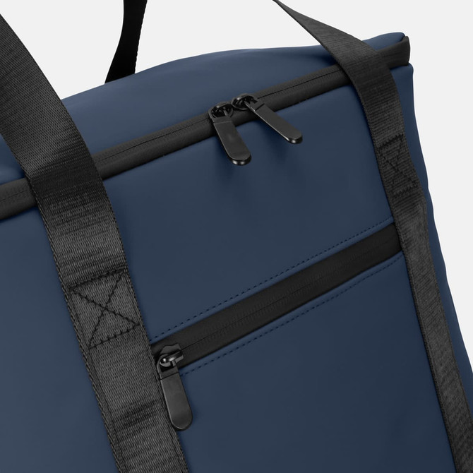 A navy soft-touch cooler bag with black zip and straps, featuring an exterior pocket. It has a logo on the front.