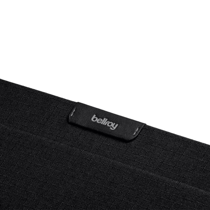 A black laptop sleeve made from textured fabric, featuring a small logo tag.