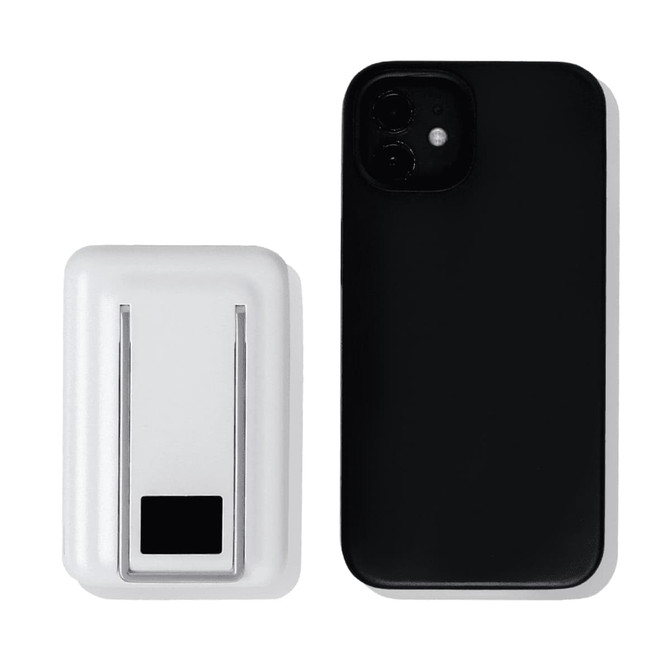A white magnetic power bank with a phone stand next to a black smartphone. The power bank features a logo.