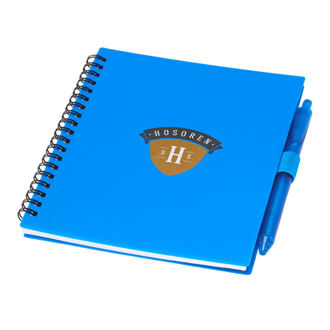 A blue journal with a spiral binding and a matching blue pen attached, featuring a logo.