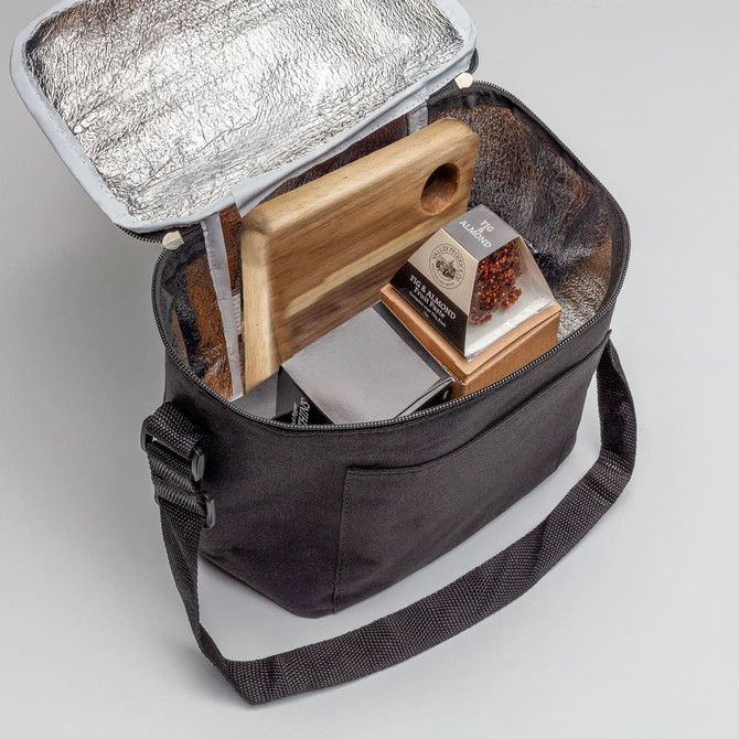 A cooler bag in black with a silver interior, containing a wooden board, snacks, and a bottle.