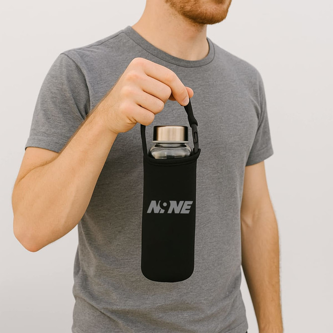 A drink bottle carrier pouch in black, featuring a handle and an attached logo, held by a person wearing a grey shirt.