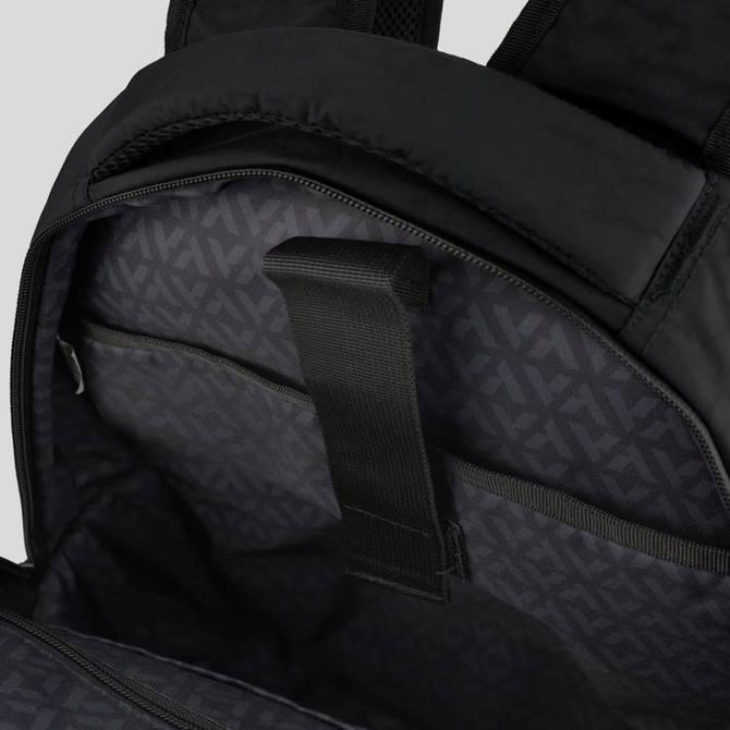 A black backpack interior featuring a dark patterned lining and a strap for securing items.