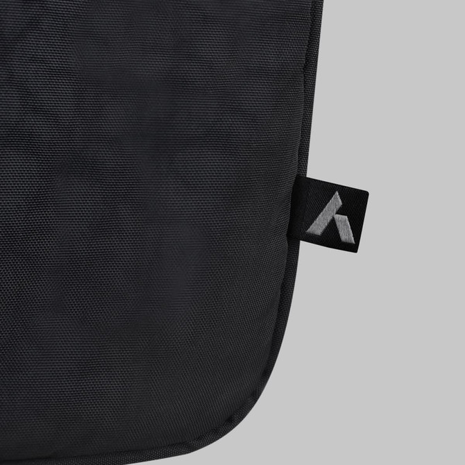 A black laptop bag features a smooth texture and a small branding tag in the corner.