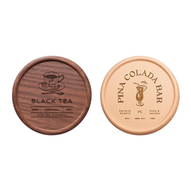 Two round wooden coasters, one in dark brown with a tea design and one in light wood featuring a tropical cocktail design.