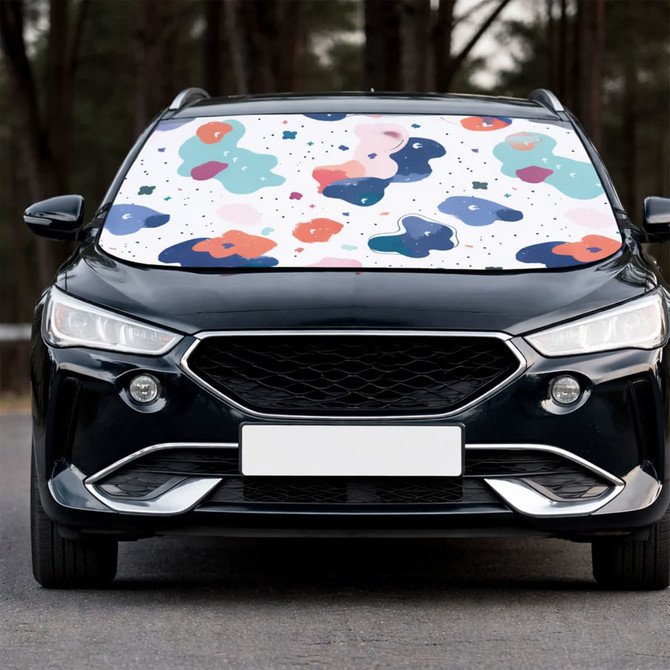 A light-blocking car sun shade featuring a colourful abstract design in pink, blue, and lavender, placed on a black car.