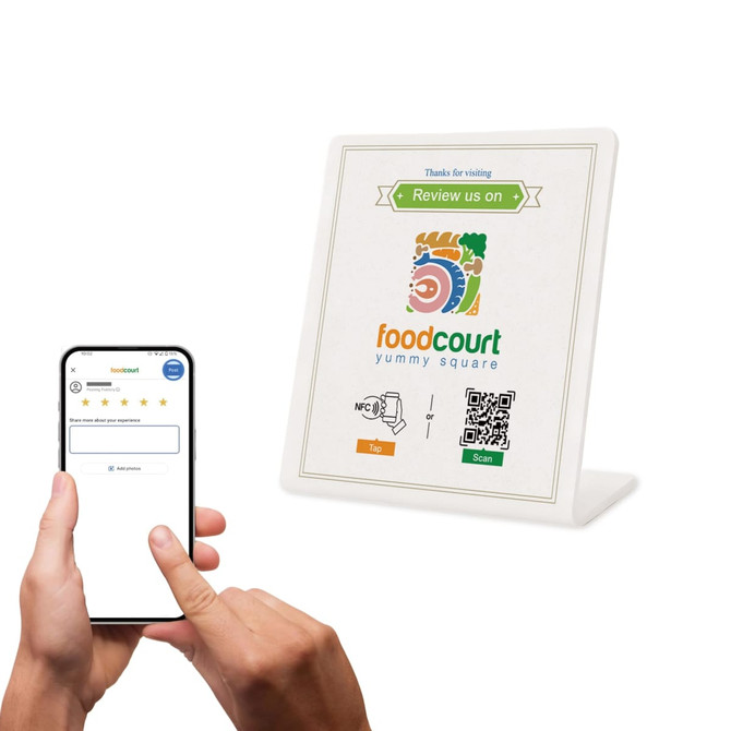 A white NFC review stand displays a QR code, next to a hand holding a smartphone with a review interface.
