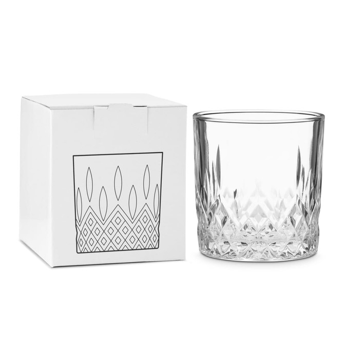 A crystal drink glass sits beside a white box featuring a geometric design. The glass has a clear, faceted finish.