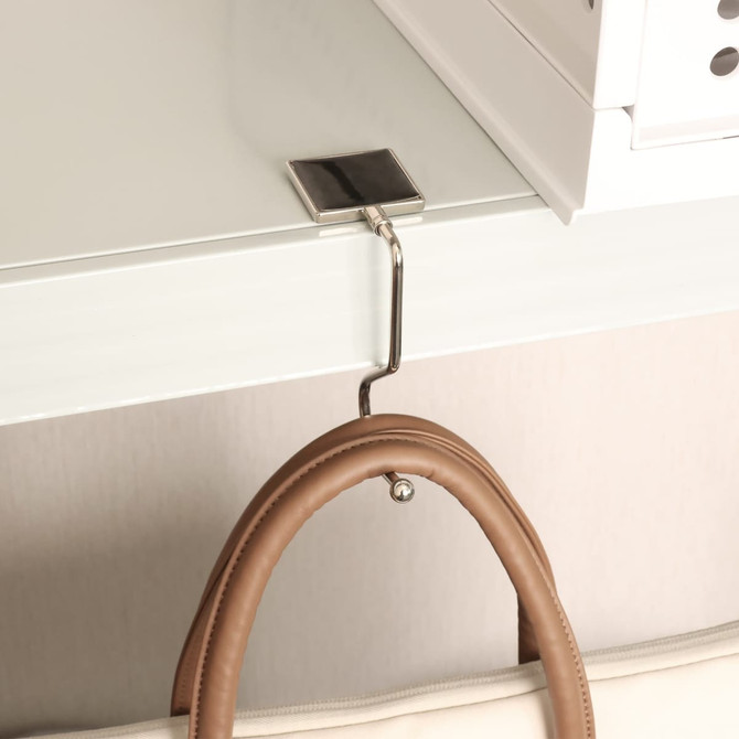 A square curved desk hook in silver, attached to a tabletop, holding a brown handbag. The product has a small logo.