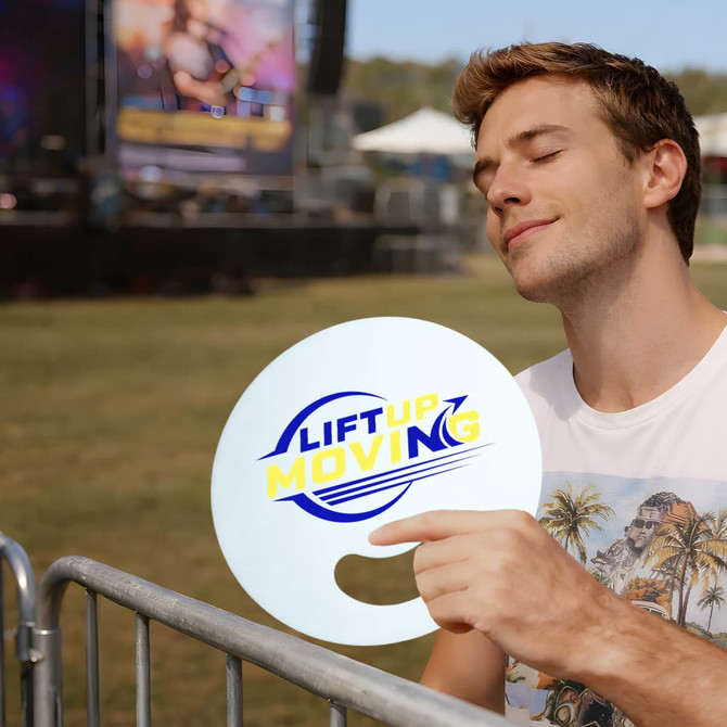 A round, white custom-shaped fan without handles being held by a man, featuring a logo design.