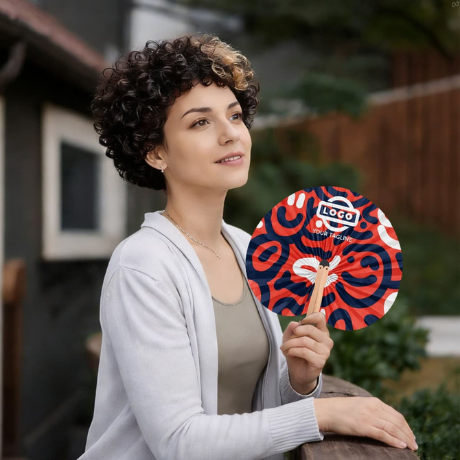 A peach-shaped wooden paper fan with red and blue patterns, held by a person with curly hair.