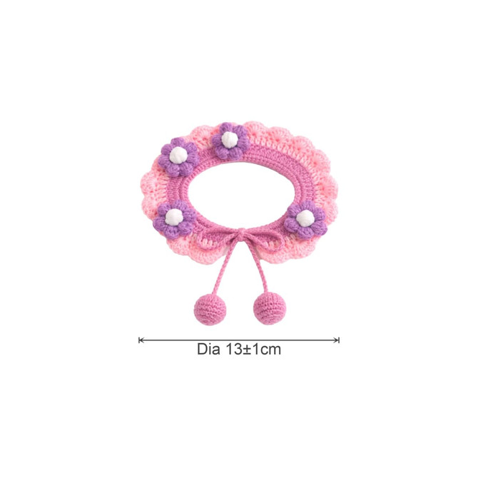 A pink and purple crochet pet bib with floral embellishments and decorative pom poms. Features a circular design measuring 13cm diameter.