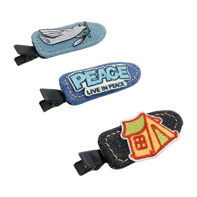 Three denim duck bill hair clips featuring various embroidered designs in blue and multi-colours. They have attached black clips.