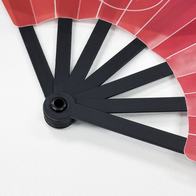 A plastic hand fan with red and white design, featuring black spokes and a circular base.