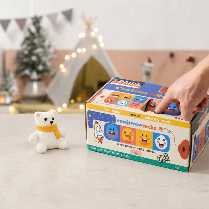 A colourful multi-compartment box with various playful emoji designs and a small white teddy bear beside it.