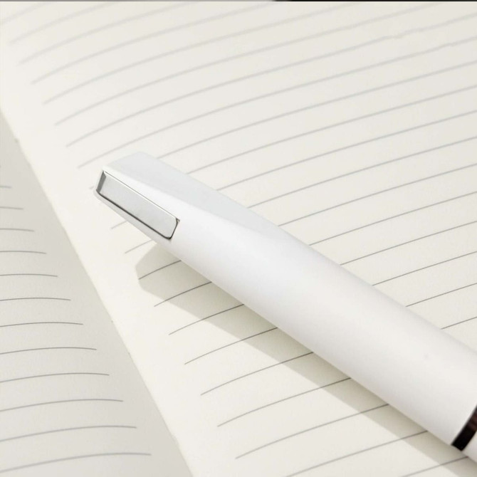 A white pen rests on a lined notebook page, featuring a sleek design and minimalistic style.
