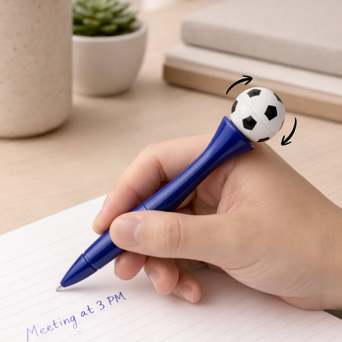 A blue pen with a spinning football on top, placed near a notebook and a small potted plant.