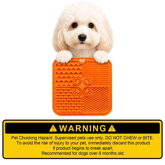 An orange 4-section lick mat with various textures held by a fluffy dog, featuring a warning label at the bottom.