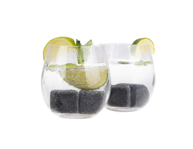 Two clear glasses filled with a refreshing drink, featuring lime slices and black ice cubes.