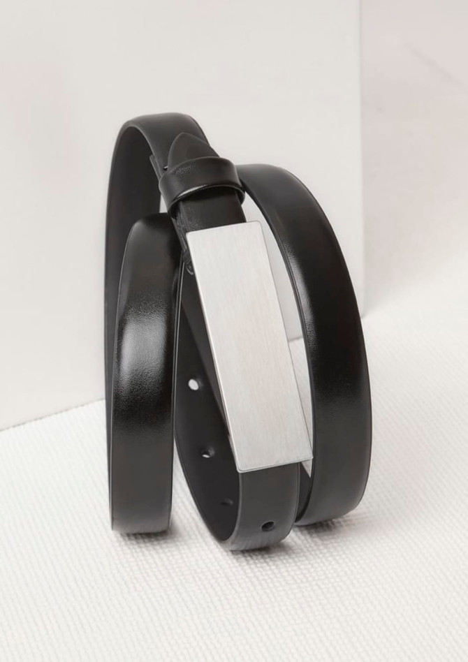 A black leather belt with a silver-tone metal embellishment, featuring a sleek and minimalist design.