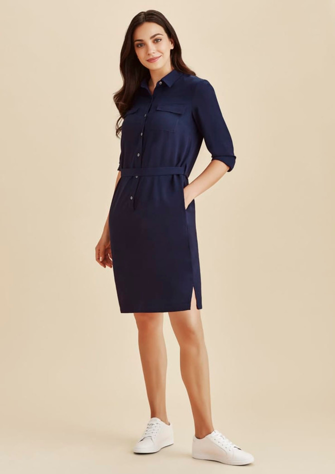 A navy blue shirt dress featuring a button-up front, belted waist, and side pockets, paired with white sneakers.