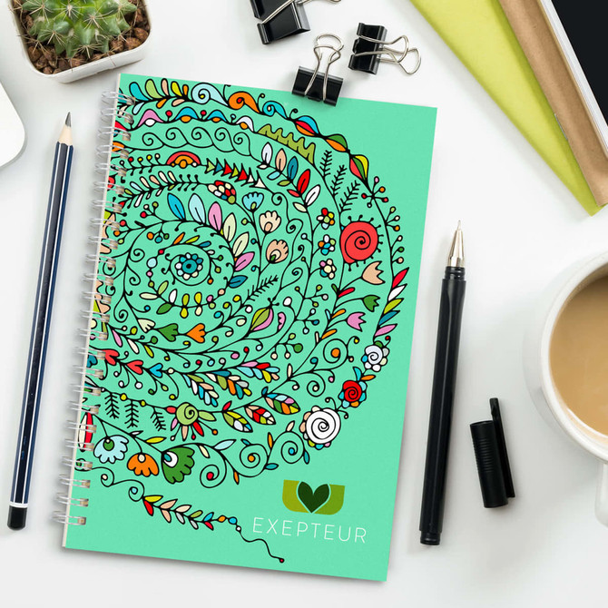 A medium-sized notebook with a spiral binding features a vibrant, abstract design in greens, pinks, and orange.