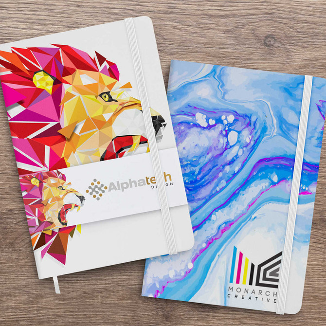 Two notebooks displayed side by side, one with a colourful lion design and the other in blue marbled pattern, both featuring logos.
