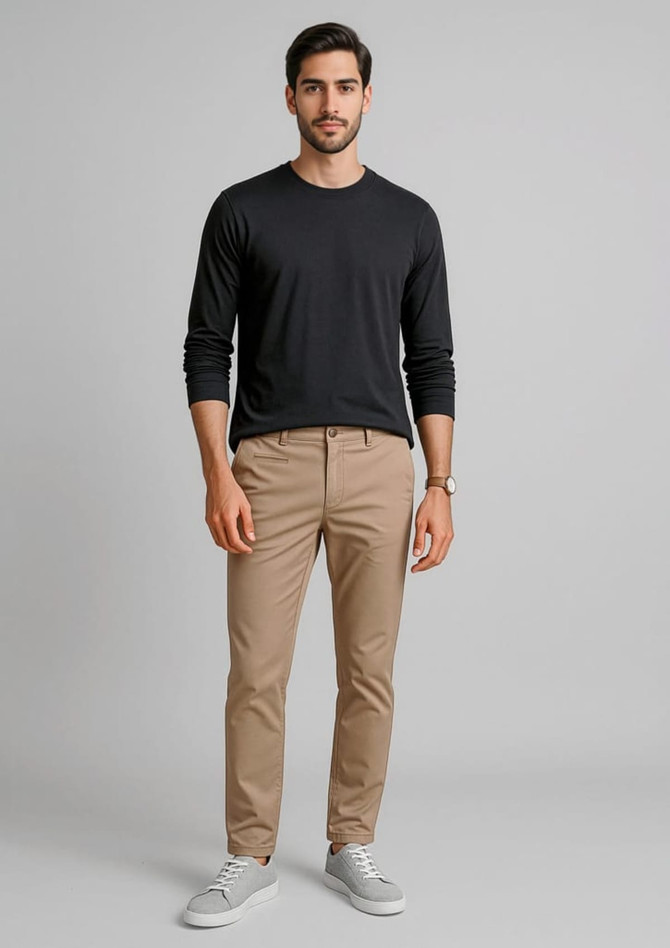 A pair of men's tapered stretch chino pants in beige, paired with a black long-sleeve shirt and white sneakers.