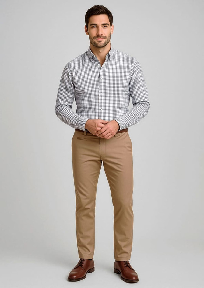 A man stands wearing a checked shirt and light brown modern stretch chino pants, with a logo on the pants.