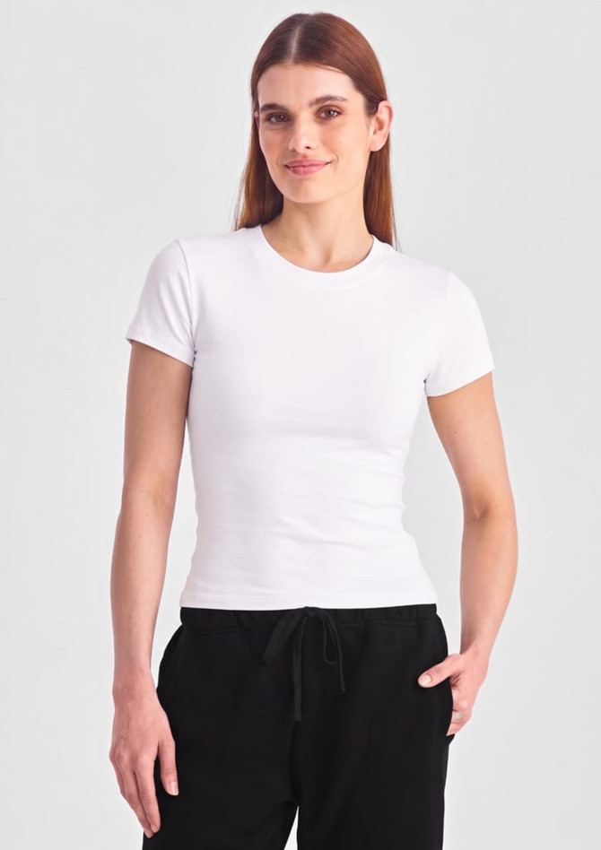A women's baby tee in white, featuring short sleeves and a fitted design, displayed on a model.