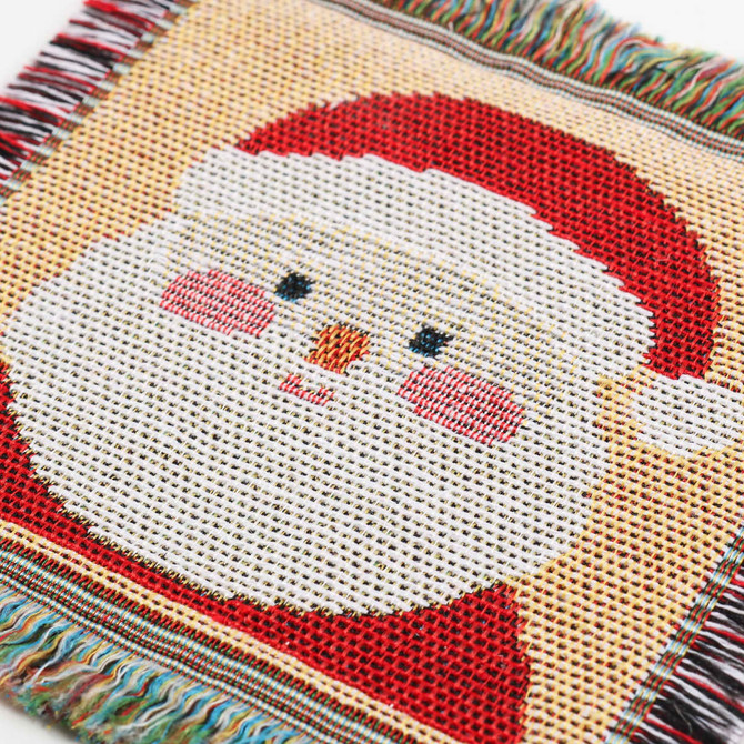 A patterned coaster featuring a festive Santa Claus design in red, white, and pink with textured fringes.