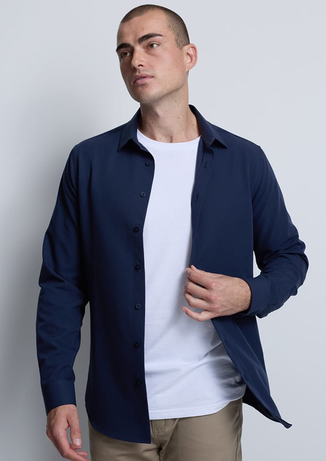 A navy long sleeve shirt is displayed, featuring a button-up front and a fitted design. The model wears a white T-shirt underneath.