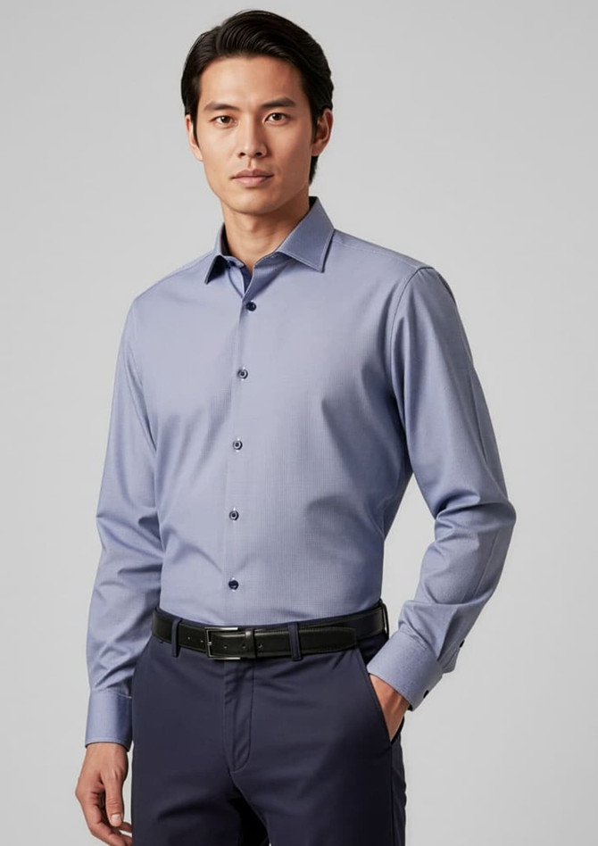 A men's long sleeve button-up shirt in a light blue colour, featuring a collar and buttoned front, worn with dark trousers.