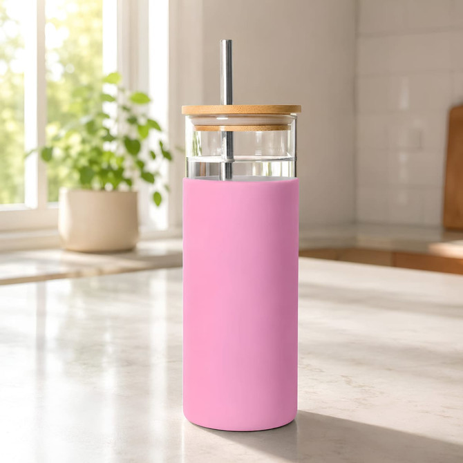 A drink bottle featuring a pink sleeve, glass body, bamboo lid, and a metal straw, set on a kitchen countertop.