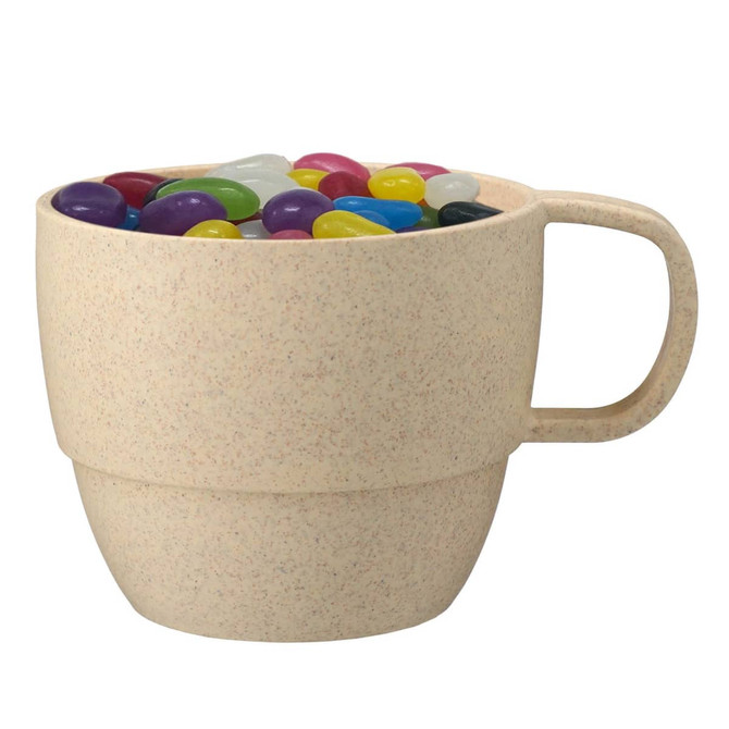 A reusable wheat straw cup in a light beige colour filled with colourful jelly beans. It features a handle and a logo.