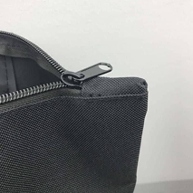 A grey nylon tote bag featuring a zipper closure and a metal zipper pull. It has a simple, minimalist design.