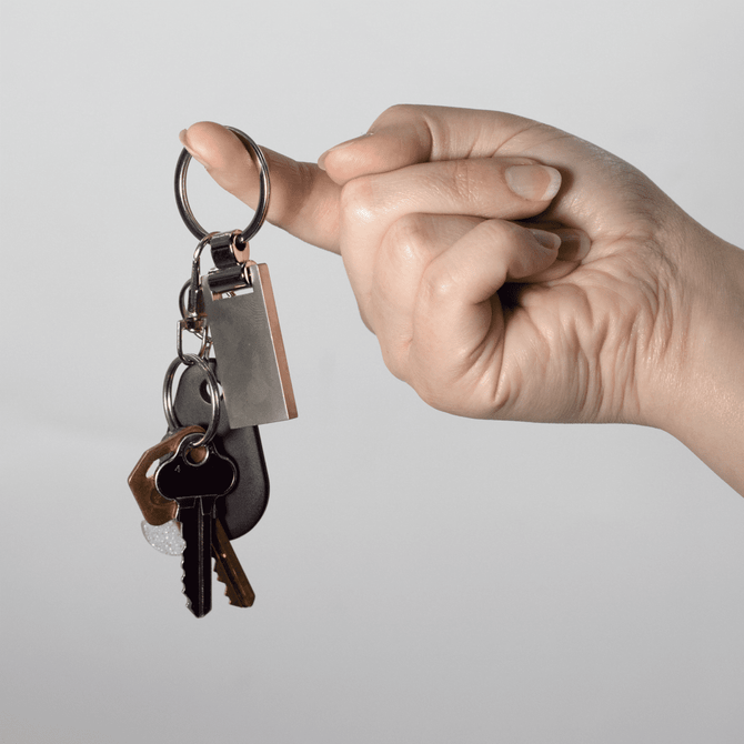 A hand holding a silver keychain with multiple keys attached, featuring a rounded key ring.