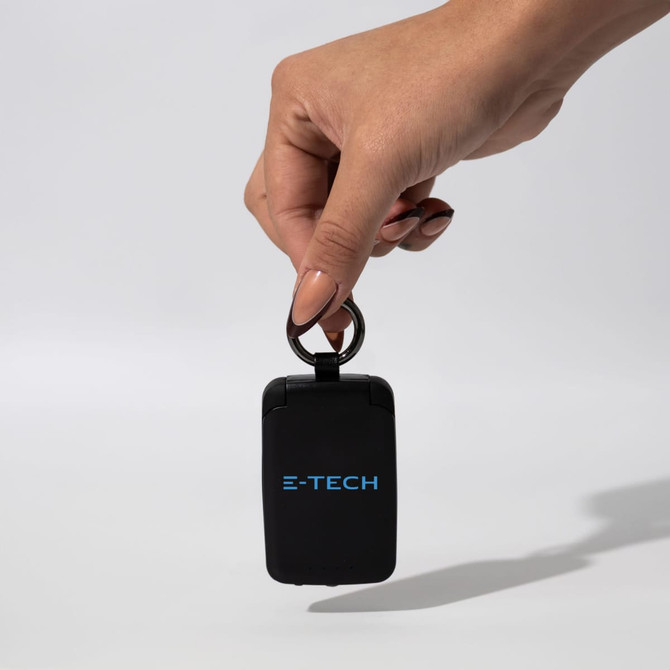 A black mini power bank with a keyring attachment, featuring a logo in blue.