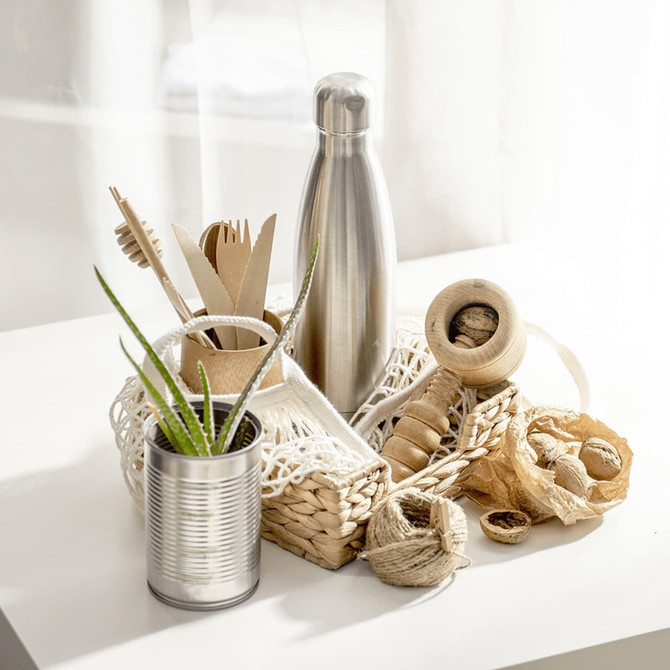 A drink bottle in a silver finish, surrounded by natural items in a decorative basket.