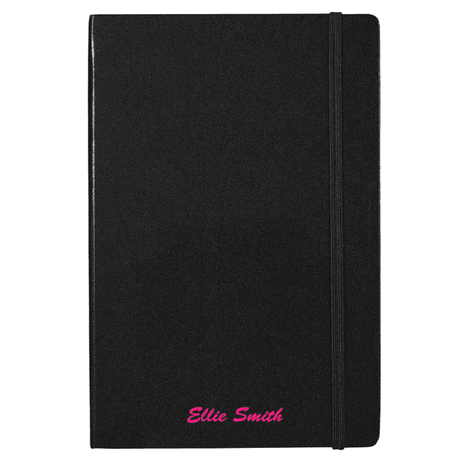 A black journal with an elastic band, featuring a custom name in pink text at the bottom. It includes a branding logo.