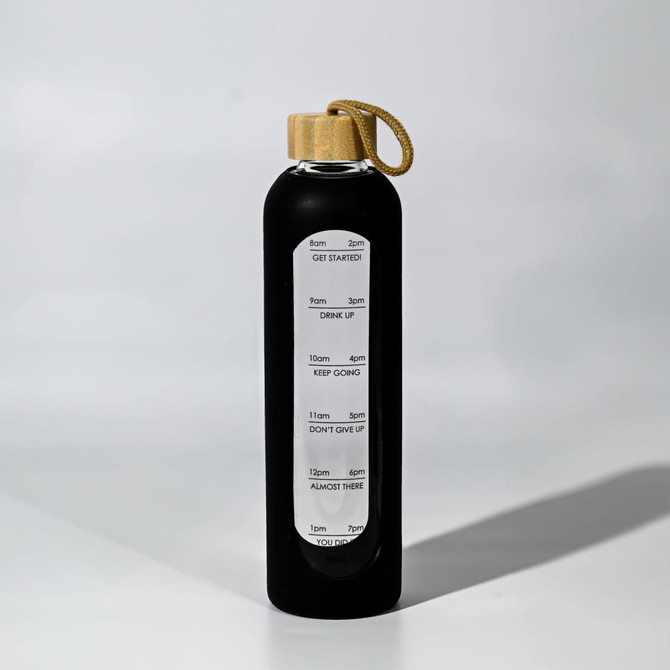 A drink bottle in black glass with a wooden lid and a rope handle, featuring measurement markings on the side.