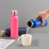 A drink bottle in pink and blue, featuring a sleek design and a metal lid, with liquid being poured into a cup.