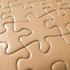 A close-up of beige jigsaw puzzle pieces with interlocking designs, featuring a smooth surface and subtle texture.