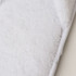 A pair of soft white hotel slippers featuring a plush texture and a branded logo on the side.