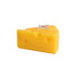 A triangular, yellow candle shaped like a cheese wedge, featuring holes and a small flag.